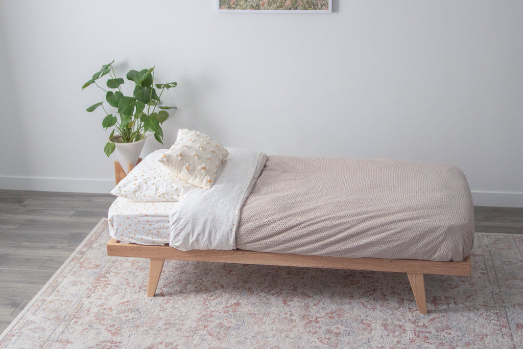 A toddler bed with legs and a mattress on top 