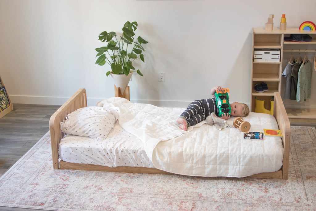 A montessori floor bed with two headboards and a little boy laying on top 