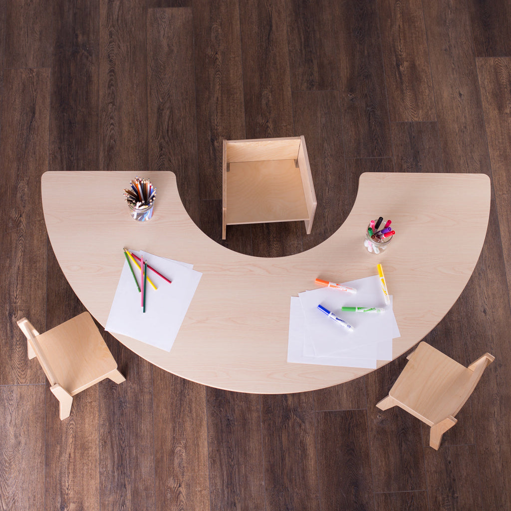 Bird's eye view of a half round table with coloring supplies